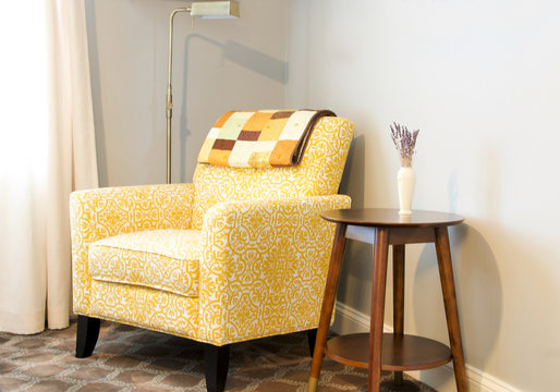 yellow upholstered armchair in room with side table