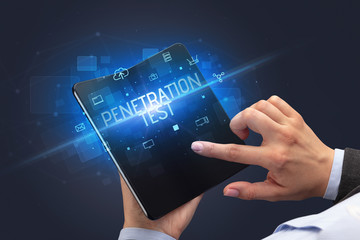 Businessman holding a foldable smartphone with PENETRATION TEST inscription, cyber security concept