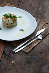 Tartar salmon with herbs on white dish
