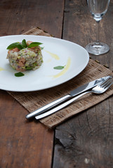 Tartar salmon with herbs on white dish