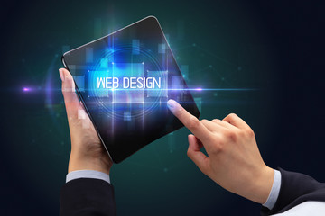 Businessman holding a foldable smartphone with WEB DESIGN inscription, new technology concept