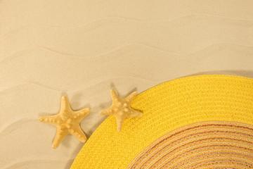 Fototapeta na wymiar Two stars and yellow hat on sand. Summer card