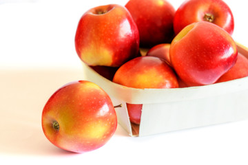 Group of fresh red apples in the basket on the white background. Healthy food concept.
