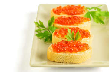 White dish with sandwitches of white bread and red caviar with parsley. Healthy food.