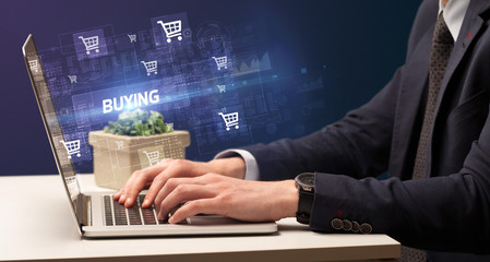 Businessman working on laptop with BUYING inscription, online shopping concept