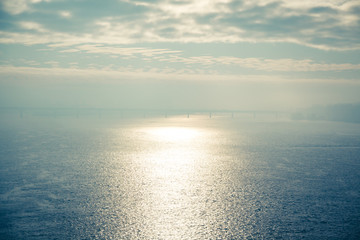 Cold early winter morning, light haze and fog rise above the calm water of the river, on the shore there are trees without leaves.Bridge and the silhouette of the buildings in the distance. Kyiv. 