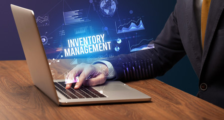 Businessman working on laptop with INVENTORY MANAGEMENT inscription, new business concept
