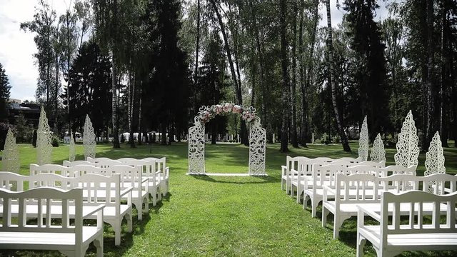Wedding ceremony in white colors. Decorated arch with fresh flowers of roses, peons, chrysanthemums and green eucalyptus. Outdoor holiday