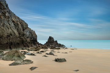 Epic beautiful sunrise long exposure landscape of vibrant sky over calm rocky sand beach