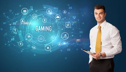 Businessman thinking in front of technology related icons and GAMING inscription, modern technology concept