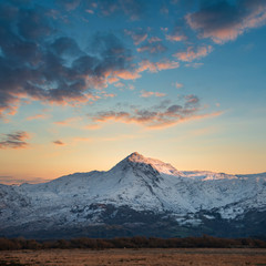 Eic landscape image of Snowdonia snowcapped mountains with dramatic sunset clouds and beautiful vibrant glow