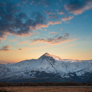 Eic landscape image of Snowdonia snowcapped mountains with dramatic sunset clouds and beautiful vibrant glow