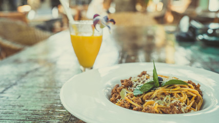Appetizing noodles on plate and juice on table. From above tasty fresh noodles on white plate and orange juice in glass