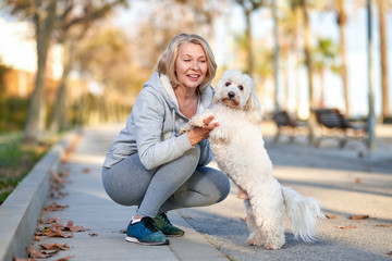 Elderly woman walking with a dog outdoors.