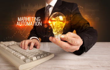 Businessman holding lightbulb with MARKETING AUTOMATION inscription, Business technology concept