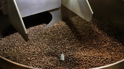 Rotating coffee roasting machine. Hand held real time shot of roasting brown coffee beans.