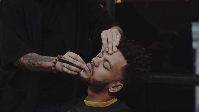 Hairdresser shaving african american man. 