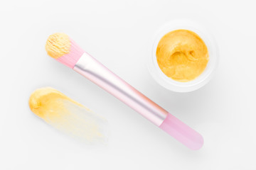 golden facial cream mask with a brush on white background