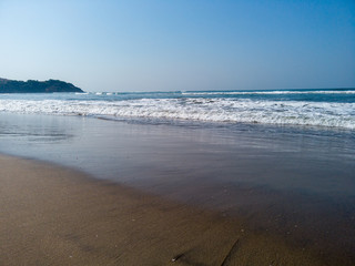 Foamy sea waves on shore. Foamy waves of clean sea water rolling on wet sandy beach on sunny day on resort
