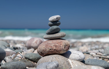 Fototapeta na wymiar Gravel / pebble beach at the southwest coast of Rhodes island near Apolakkia with multi colored ocean water and small stone figures