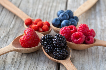 Ripe berries in wooden spoons