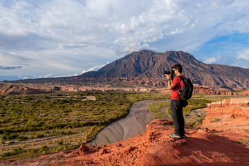Photographer taking pictures of red earth formations in Quebrada de las Conchas, Salta Region,...