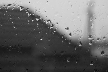 Window in raindrops, water drops on glass, bw photo.
