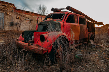 Old rusty broken abandoned Soviet fire truck on evening sunset