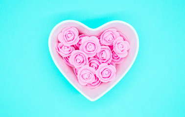 Pink flowers in a heart-shaped casket against a bright mint background. Valentines day background. Mother's Day, March 8th background. Flat lay, top view