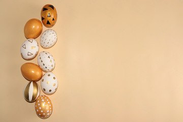 Decorated golden Easter eggs on a yellow background. Minimal holiday concept. Happy Easter background with copy space, place for text. Creative painting of eggs at home.