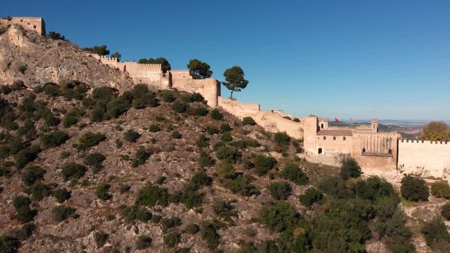 Aerial close by lateral view of an old medieval castle on a v shaped rocky mountain