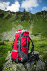 Red backpack on mountains background. Hiking in the mountains in the summer with a backpack