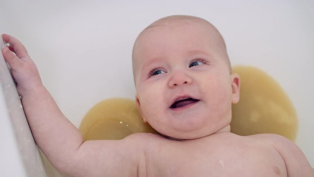 Six Month baby boy is happy and smiles during bath time slow motion 8K