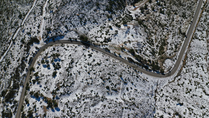 Aerial drone photo of curvy icy road in famous mountain of Penteli covered in white snow during winter time, Attica, Greece