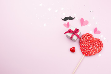 The concept of Valentine Day. Gift box, lollipop heart-shape and other love objects on pink background. Top view. Copy space.