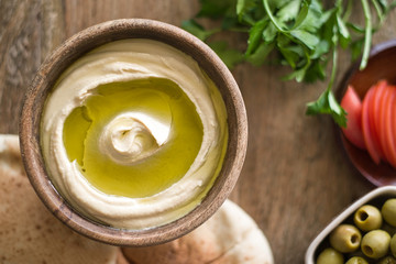 Home made humus with olive oil on wooden background.