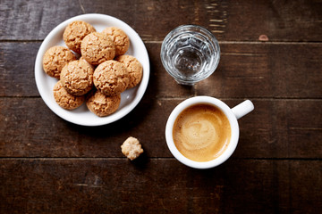 Cup of coffee with amaretti (Italian biscuit) on rustic wooden background. Top view. Copy space.