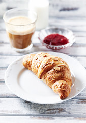 Croissant with hot chocolate. White wooden background.