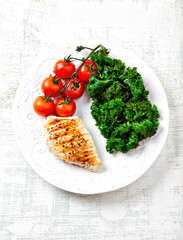 Grilled Chicken Breast with roasted Cherry Tomatoes. Bright wooden background. Top view.