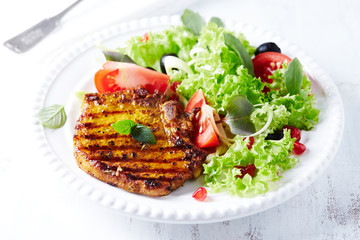 Grilled pork steak with fresh salad. White background