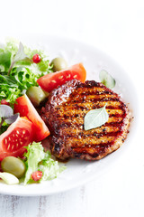 Grilled pork steak with fresh salad. White background.