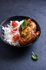 Spicy chicken with rice on black stone background. Close up.