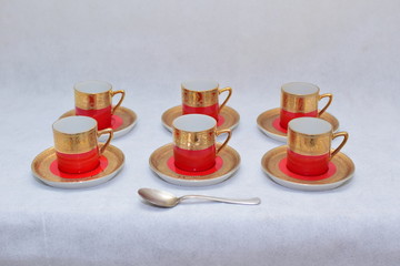 Mock up / design set of elegant and traditional colorful Red and gold traditional elegant coffee cup & Tea cup on cup's plate beside the hot tea jar container , design/ drink-ware