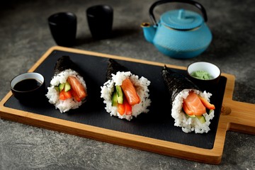 Hand - roll sushi, temaki sushi with salmon, cucumber and bell pepper.