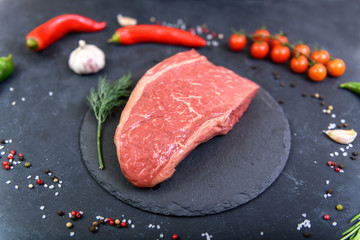 Raw fresh marbled meat and seasonings on dark background top view