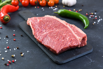 Raw fresh marbled meat and seasonings on dark background