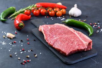 Raw fresh marbled meat and seasonings on dark background