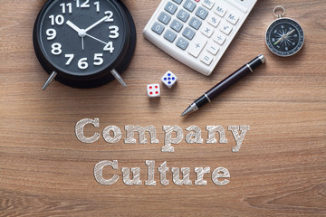 Company Culture written on wooden table with clock,dice,calculator pen and compass
