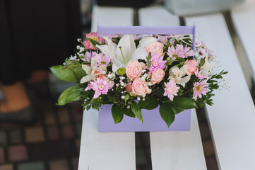 Fresh flowers close-up in a wooden basket for congratulations. Wedding gift of flowers: roses, chrysanthemums, violets, lilies. Photography, concept.