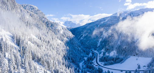 Magical Switzerland winter lake in the middle of the Alps surrounded by the magical forest covered in snow.